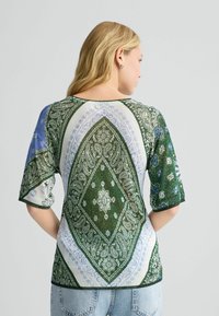 Lühikeste varrukatega pluus, millel on roheline ja sinine paisley muster, ümmargune kaelus ning kontrastsete äärtega viimistlus.