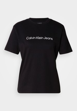 Fekete pamut póló rövid ujjakkal, kerek nyakkal, és a mellkason középen elhelyezett fehér "Calvin Klein Jeans" logóval. Sima textúra.