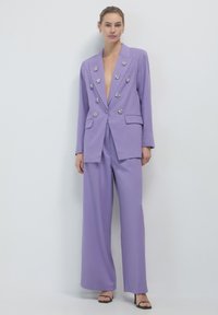 Completo lavanda realizzato in tessuto testurizzato con blazer a profondo scollo a V e pantaloni a gamba ampia, adornato con accenti floreali argentati.