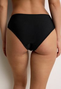 Black high-waisted underwear made of smooth fabric, featuring scalloped edges and a modest cut at the back.