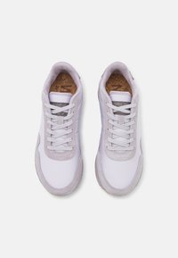 Vita och ljusgrå sneakers med en slät syntetisk ovandel och mockadetaljer, med snörning och en korksula.