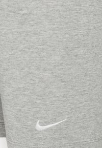 Shorts en coton gris avec une finition texturée, ornés d'un petit logo Nike blanc sur l'ourlet. Design simple, adapté pour un usage décontracté.