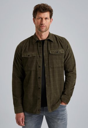 Olijfgroene flanellen shirt met een geruit patroon, voorzien van twee borstzakken en zwarte knopen, gedragen over een zwart T-shirt.