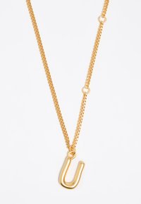 Collar de color dorado con una cadena gruesa y un colgante en forma de U. La cadena tiene eslabones redondeados y es suave al tacto.
