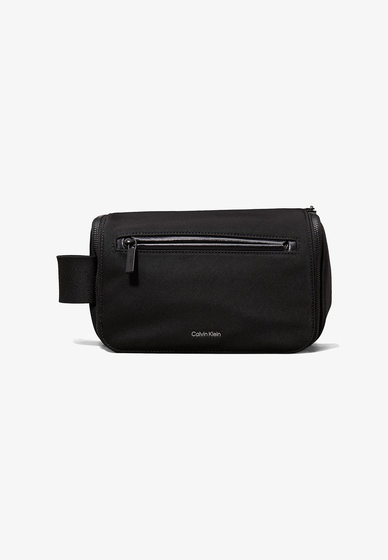 Borsa da toiletta rettangolare nera in tessuto testurizzato, con una tasca frontale con zip, manico laterale e logo Calvin Klein sulla parte anteriore.