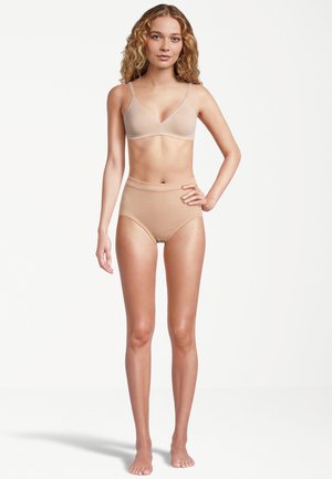 Nagie bezszwowe braletki z regulowanymi ramiączkami i wysokim stanem do kompletu, wykonane z miękkiego, rozciągliwego materiału.