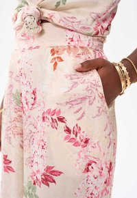 Blommönstrat tyg med rosa, röd och grön nyanser. Hög midja med sidfickor. Slät textur och lätt material.