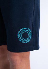 Granatowe szorty wykonane z bawełny o miękkiej teksturze, z okrągłym turkusowym logo na dolnej części nogawki. Doły nogawek wykończone prostym cięciem.