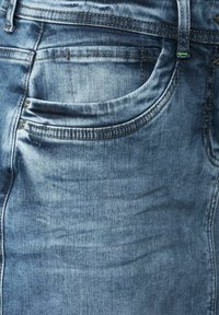 Jeans de mezclilla azul con un diseño clásico de cinco bolsillos, con un leve desgaste y costuras en contraste. Incluye dos remaches metálicos en el bolsillo.