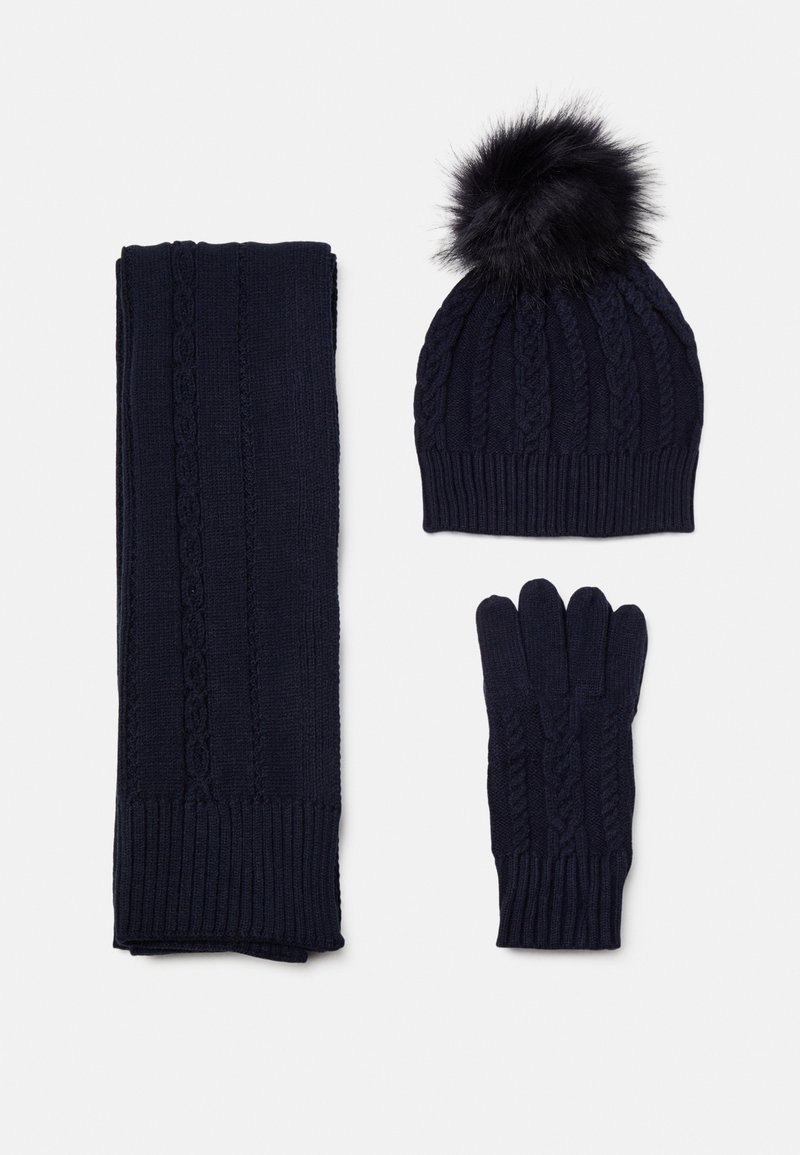 Ensemble d'hiver en maille bleu marine avec des motifs torsadés, comprenant un bonnet à pompon, des gants et une longue écharpe sur fond blanc.