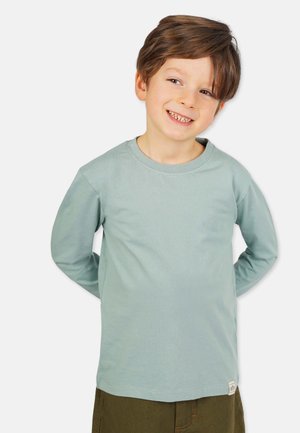 Lyseblå langærmet T-shirt lavet af blød bomuld. Har rund halsudskæring og et lille mærke ved kanten. Glat tekstur, afslappet pasform.