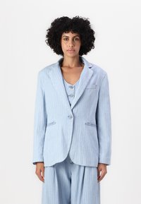 Blazer a righe azzurre chiaro realizzato in tessuto morbido, con colletto a punta, bottoni frontali e due tasche laterali. Abbinato a pantaloni coordinati.