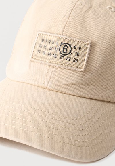Μπεζ καπέλο μπέιζμπολ με ορθογώνιο έμβλημα που δείχνει αριθμούς από 0 έως 23 και έναν κυκλωμένο αριθμό 6 σε μαύρη κλωστή.