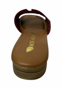 Sandalia color burdeos con una tira ancha y una suela de plataforma texturizada en color tostado. Logotipo dorado "MIS MAM" grabado en la plantilla. Diseño plano, punta abierta.