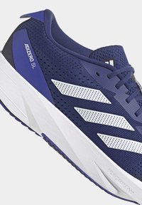 Chaussure de course Adidas bleu marine avec semelle blanche, bandes blanches perforées et étiquette "ADIZERO SL" sur le côté.