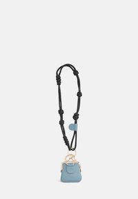 Petit sac en cuir bleu sur un collier en corde noire, doté d'une pince de ton or et d'accents noués tout au long du design de la sangle.