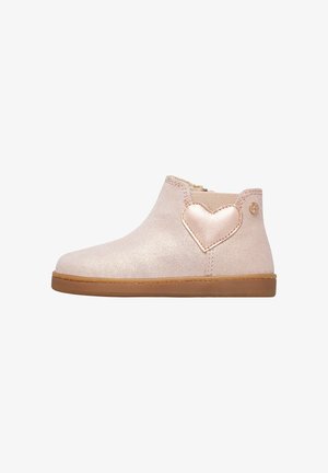 Bottines à paillettes roses avec côtés élastiques, semelle beige, et un accent en forme de cœur métallique sur le côté extérieur, présentant une texture lisse et une forme arrondie.