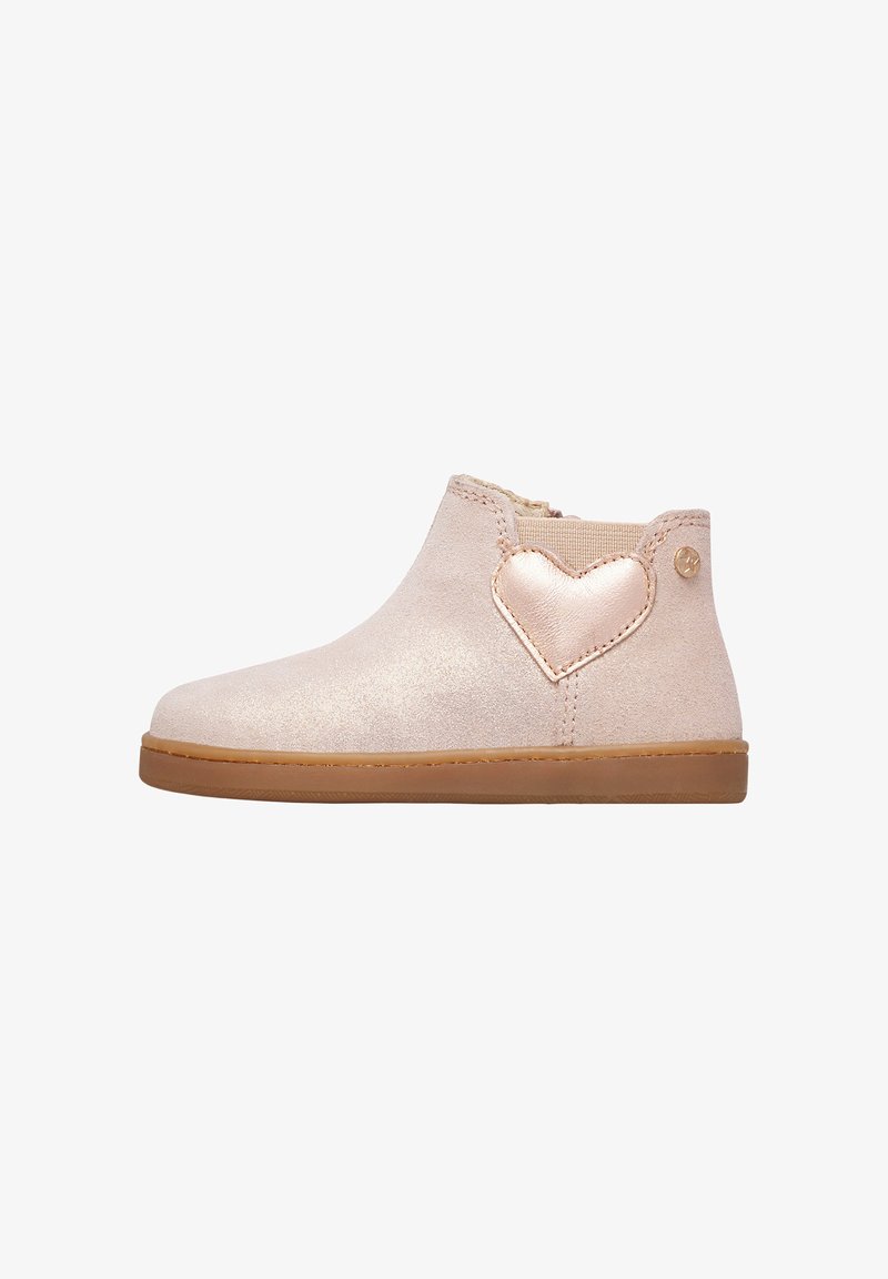 Bottines à paillettes roses avec côtés élastiques, semelle beige, et un accent en forme de cœur métallique sur le côté extérieur, présentant une texture lisse et une forme arrondie.
