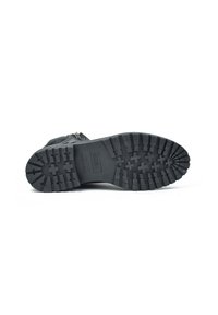 Semelle de botte en caoutchouc noir avec des crampons profonds, dotée de grips en motif croisé. Étiquette estampillée indiquant "Fabriqué en Espagne" près du centre.