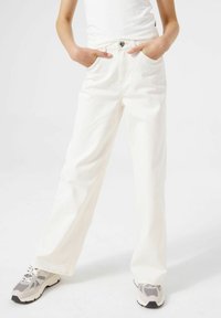 Jeans anchos de tiro alto en color blanco con cierre de botón y bolsillos laterales, hechos de una tela de mezclilla texturizada.