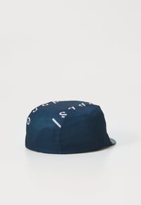 Navy blue cycling cap made of textured fabric, featuring white printed text. Rounded top with a small, curved brim.