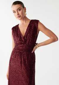 Burgundia värvi sädeluskleit sügava V-dekolteega, voogavate õlgadega ja kogutud taljega, millel on voolav seelik, kaunistatud säravate sädemetega.