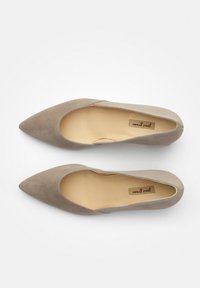 Ballerines en daim beige à bout pointu avec un intérieur lisse, des coutures minimales et une semelle plate. L'étiquette de la marque est visible à l'intérieur.