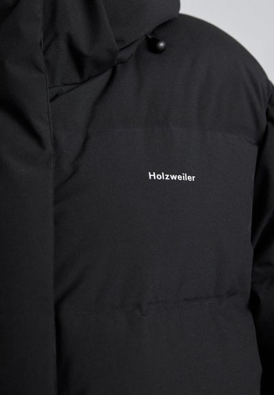 Black puffer jacket with a hood, featuring a smooth fabric texture and a small white "Holzweiler" logo on the chest.
