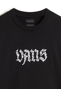 Zwarte katoen t-shirt met "VANS" tekst in witte en gele bloemenborduursel. Ronde halslijn en korte mouwen.