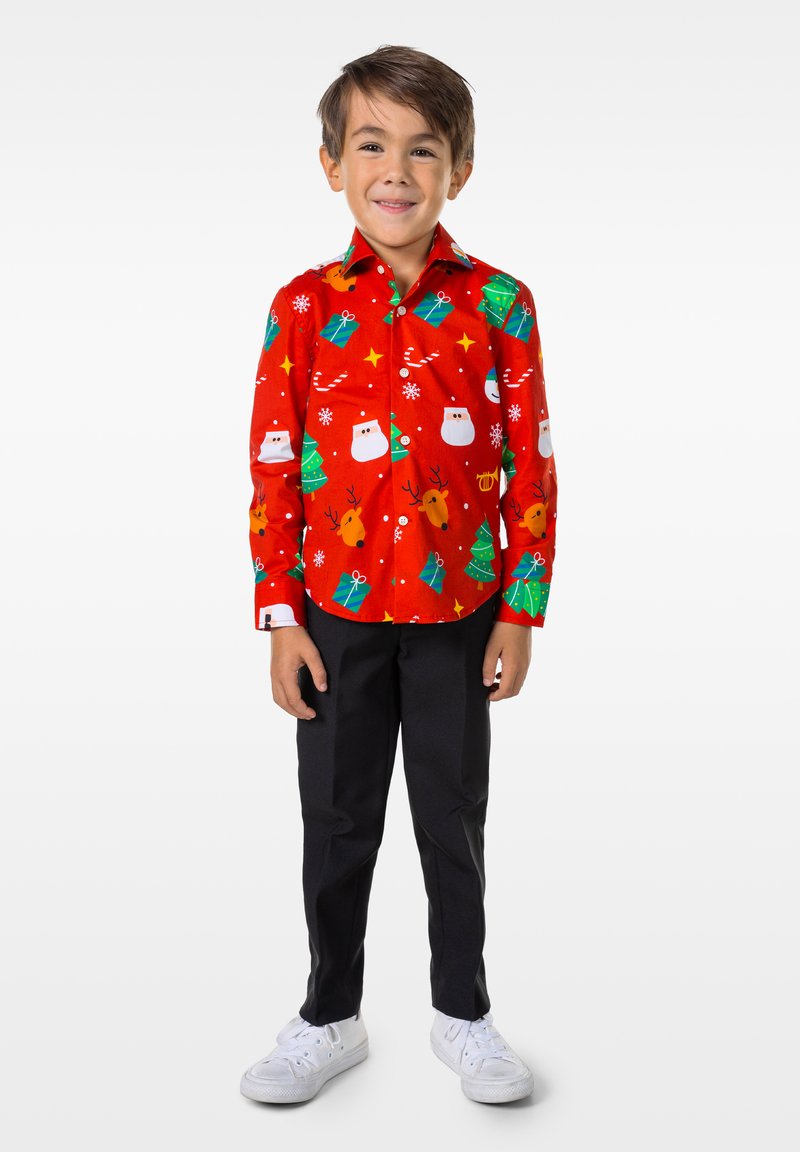 Camisa roja abotonada con varios estampados festivos, incluyendo muñecos de nieve, renos y árboles de Navidad, combinada con pantalones negros y zapatos blancos.