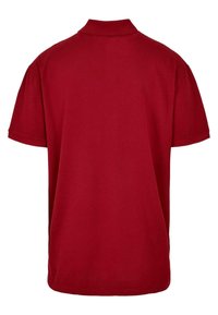 Rød polo skjorte med klassisk krage, kort ermer og en glatt bomullstekstur. Designet er enkelt uten mønstre eller utsmykninger.
