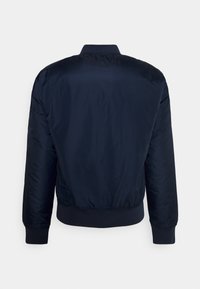 Marinblå bomberjacka med en slät, glänsande yta, ribbstickade muddar och fåll samt en klassisk design. Har dragkedja fram och en strömlinjeformad silhuett.