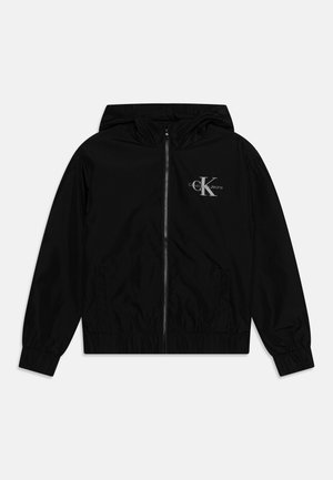 Veste à capuche noire avec fermeture éclair à l’avant, poignets élastiques, deux poches avant et logo "Calvin Klein Jeans" sur la poitrine gauche.