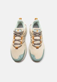 Baskets de sport en maille beige avec des accents turquoise, des lacets gris et des touches orange. Bout arrondi et semelle texturée pour une meilleure adhérence.