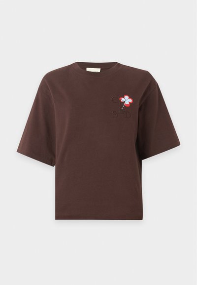 Καφέ κοντομάνικο crop t-shirt με μικρό κεντημένο κόκκινο και λευκό λουλούδι και κεντημένα γράμματα στο αριστερό στήθος.