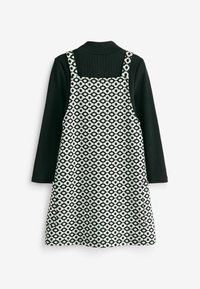 Haut noir à manches longues superposé avec une robe sans manches à motifs floraux noir et blanc avec bretelles.