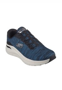 Zapatilla deportiva azul y negra con parte superior de punto texturizado, suela acolchada ligera y cordones negros; presenta un logo plateado en el costado.