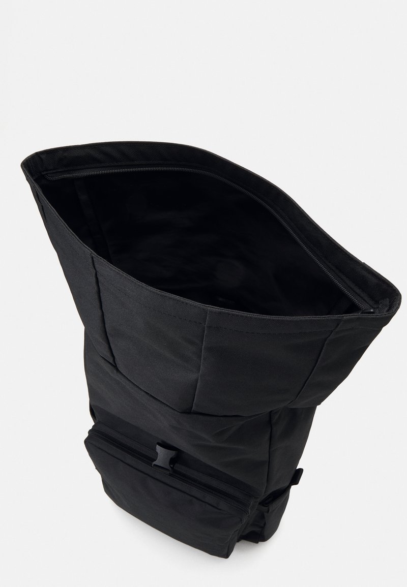 Sort rygsæk med et højt, slankt design. Har en lynlåslukning, en lille frontlomme og et struktureret stofudvendig.