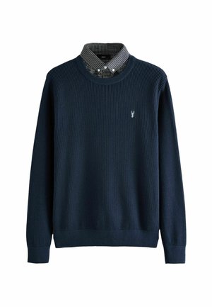 Sötétkék bordázott pulóver kerek nyakkal, alatta kockás galléros inggel, a mellkason egy kis homár emblémával.