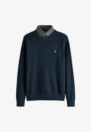 Sötétkék bordázott pulóver kerek nyakkal, alatta kockás galléros inggel, a mellkason egy kis homár emblémával.