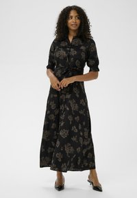 Czarna sukienka w kwiatowy wzór z krótkimi puff sleeves, kołnierzykiem i paskiem w talii. Wykonana z lekkiego materiału, ma fason pełnej długości i guziki.