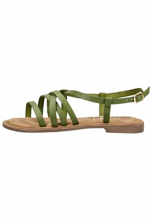 Sandale plate verte avec plusieurs fines lanières et une boucle à la cheville sur une semelle marron, vue de côté sur un fond blanc.