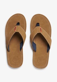Chanclas de cuero marrón con una correa de tela azul en el dedo, con costuras decorativas y un logo circular en la plantilla. Diseño plano y casual.