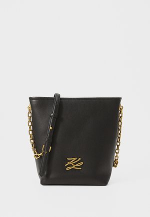 Schwarze Leder-Eimer-Tasche mit goldenen Kettenakzenten, einem abnehmbaren Schultergurt und einem geprägt Logo auf der Vorderseite. Glatte Textur, minimalistisches Design.