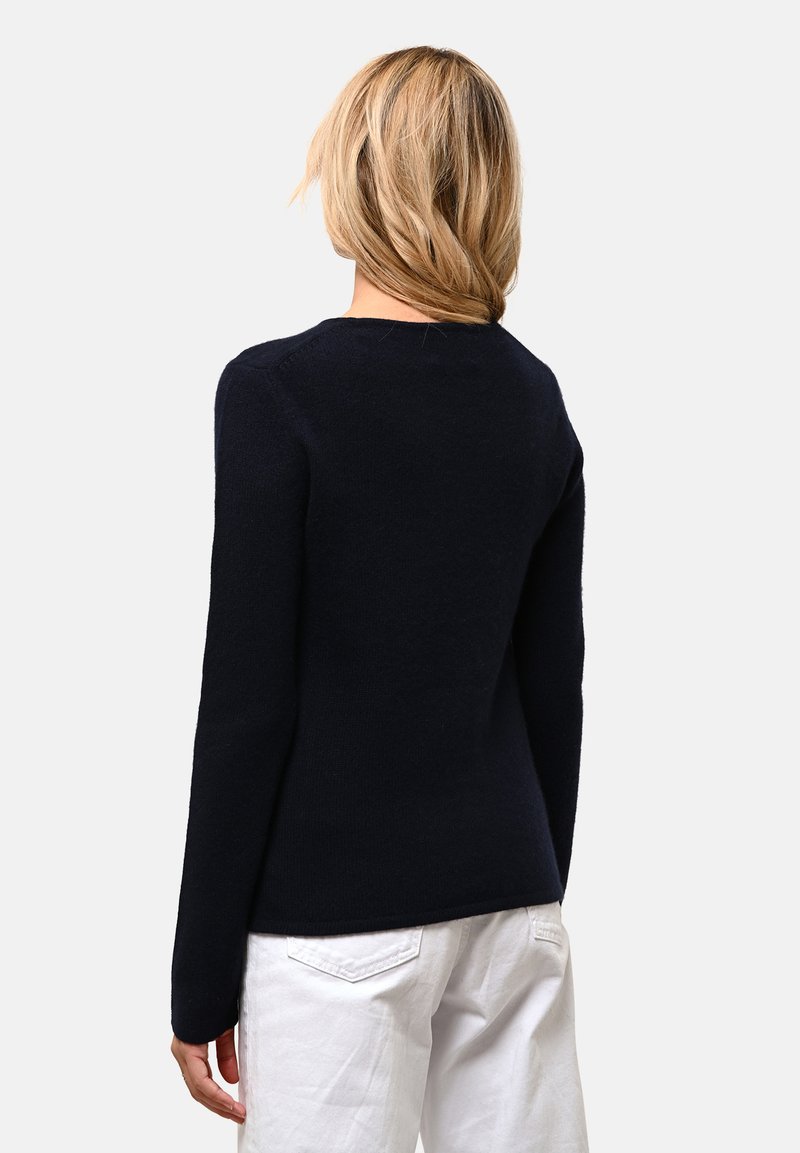 Pull en maille bleu marine avec un col rond et des manches longues. Texture douce et forme ajustée, avec un ourlet côtelé.
