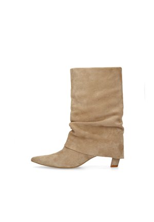 Botte mi-mollet en daim beige, à bout pointu et petit talon kitten bas, présentée sur un fond blanc.