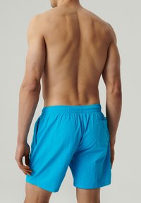 Krótki strój kąpielowy w jasnoniebieskim kolorze, z elastycznym pasem, bocznymi kieszeniami i jedną kieszenią z tyłu, charakteryzujący się lekkim i gładkim materiałem.