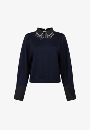 Marineblaues Sweatshirt mit schwarzem Kragen, das aufwändige Perlenverzierungen aufweist. Langer Ärmel mit kontrastierenden schwarzen Bündchen.