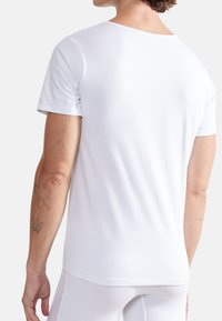 Weißes Kurzarm-T-Shirt, runder Halsausschnitt, leichtes Baumwollmaterial, glatte Textur, mit Tattoos am Arm.