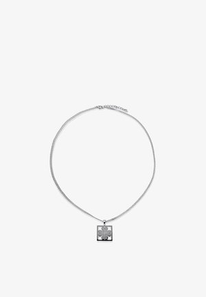 Hopeinen ketjukaulakoru, jossa on nelilehtistä apilaa esittävä kaiverrettu neliönmuotoinen riipus, valkoisella taustalla esitettynä.